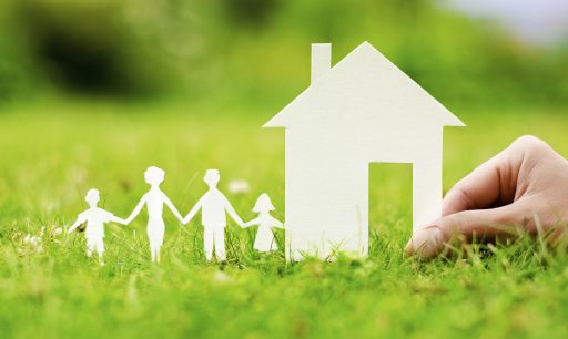 cut-out of paper house and family on grass