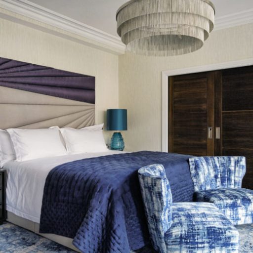 photo of bed and two blue arm chairs