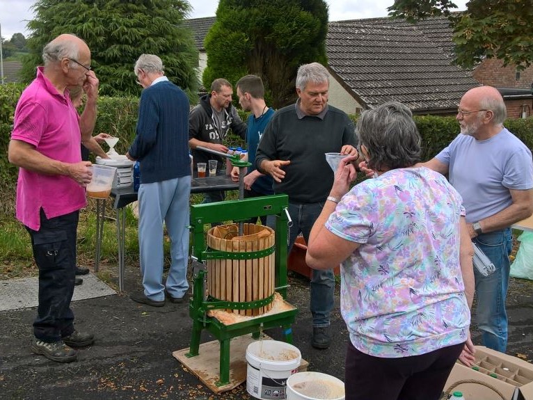 People gathering and pressing apples