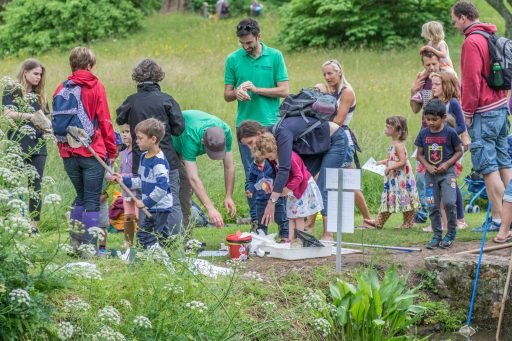 Adults and children looking at items found in the river