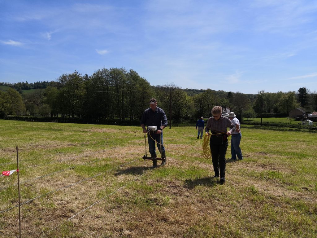 Volunteers using rope and geophysical survey equipment in a field close to Dunkeswell Abbey