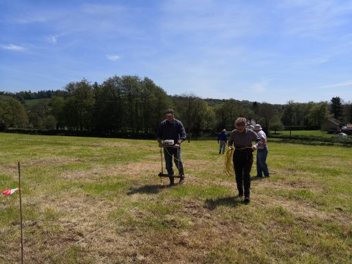Volunteers using rope and geophysical survey equipment in a field close to Dunkeswell Abbey