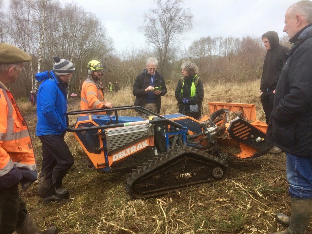 A group gathering around some farm machinery