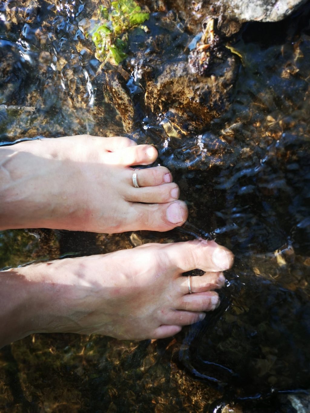 Bare feet paddling in clear shallow water