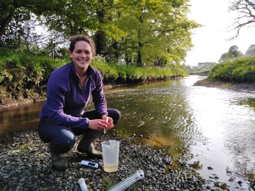 woman knelt beside river Culm sampling
