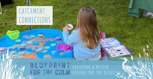 child sat on the floor beside a blue paddling pool fishing and identifying bugs