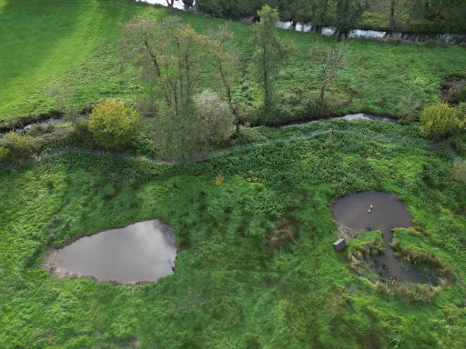 two ponds in a field alongside a river