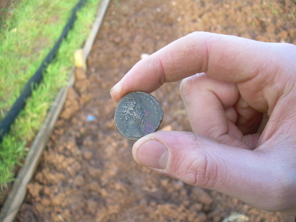 Hand holding a Roman coin between his finger and thumb