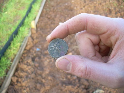 Hand holding a Roman coin between his finger and thumb