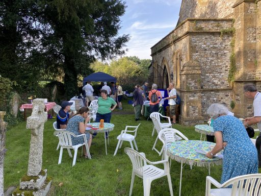 People sitting at tables outside Dunkeswell Abbey Church chatting and drinking