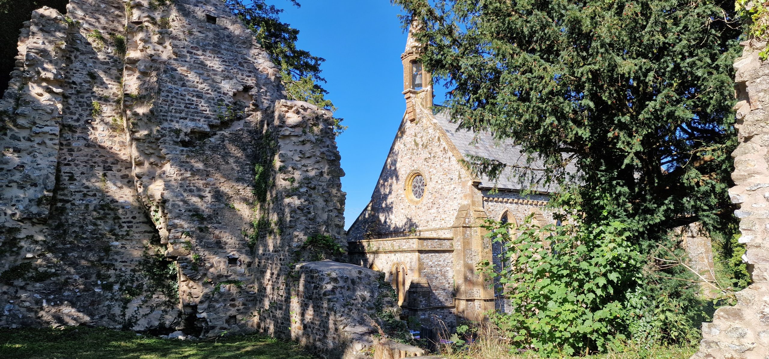 Dunkeswell Abbey ruins with church in the background
